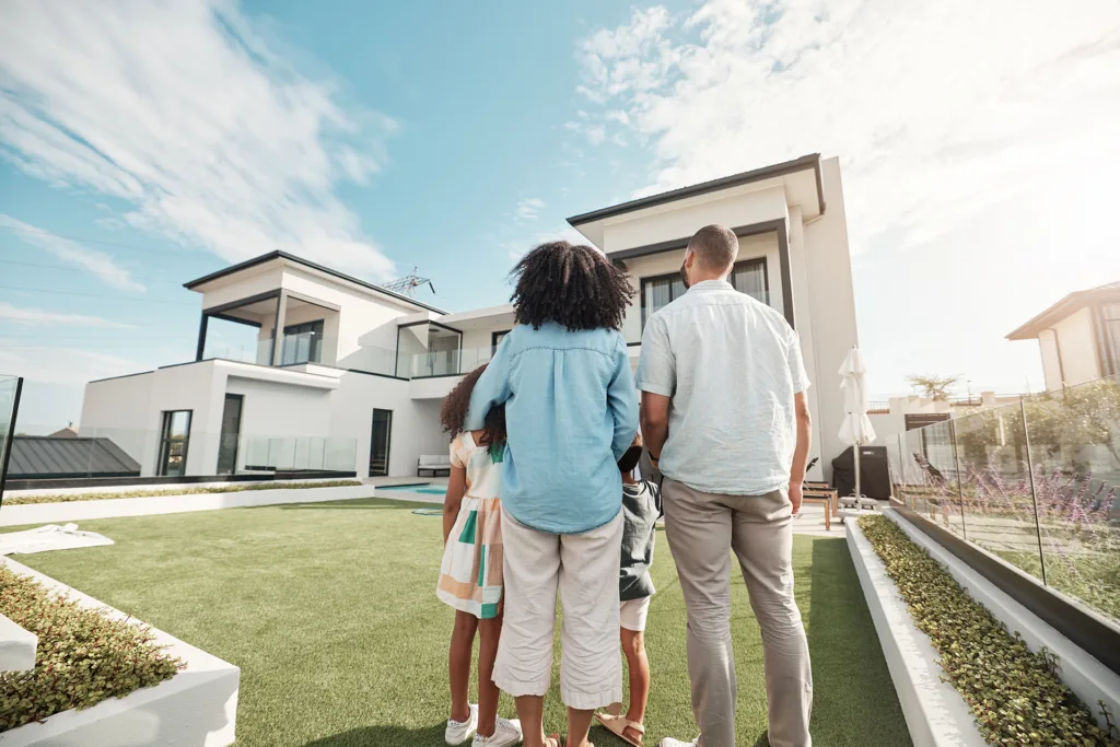 Familie mit zwei Kindern vor einem modernen Neubau mit Garten